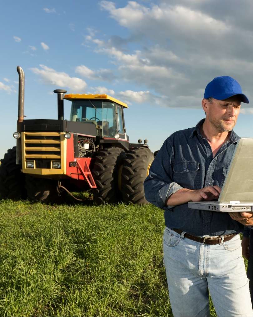 A man operating a laptop beside a tractor